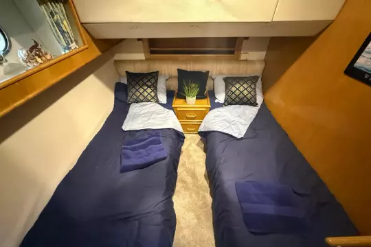 Cozy twin cabin in 1989 Fairline 50 yacht with blue bedding and decorative pillows.