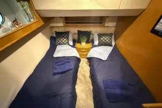 Cozy twin cabin in 1989 Fairline 50 yacht with blue bedding and decorative pillows.