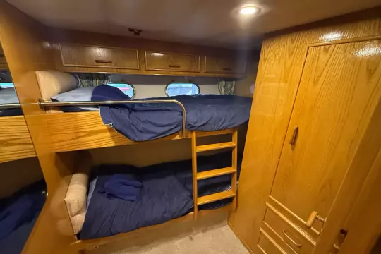 Cozy cabin with wooden bunk beds and storage in 1989 Fairline 50 yacht.