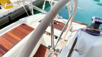 Steering wheel of 2011 Jeanneau Sun Odyssey 409 sailboat, docked with wooden deck.