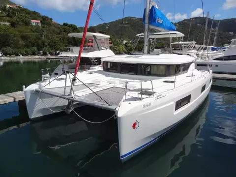 2020 Lagoon 46 catamaran docked in a scenic marina with lush hills.