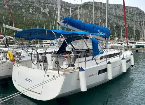 2019 Jeanneau Sun Odyssey 440 sailboat docked in a marina, featuring blue canopy and sails.