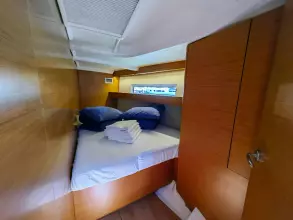 Cabin interior of 2019 Jeanneau Sun Odyssey 440 yacht with cozy bed and wooden finish.