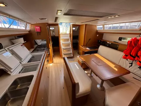 Interior of 2019 Jeanneau Sun Odyssey 479 yacht, featuring kitchen, dining area, and stairs.