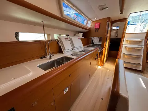 Interior of 2019 Jeanneau Sun Odyssey 479 yacht, featuring modern kitchen and wooden cabinetry.