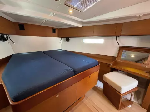 Luxurious cabin interior of 2019 Jeanneau Sun Odyssey 479 yacht with double bed and vanity.