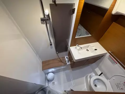 Bathroom interior of 2019 Jeanneau Sun Odyssey 479 yacht, featuring shower, sink, and toilet.