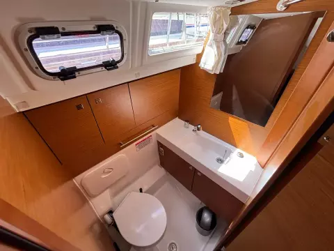 2019 Jeanneau Sun Odyssey 479 bathroom with wooden cabinetry, sink, and toilet.