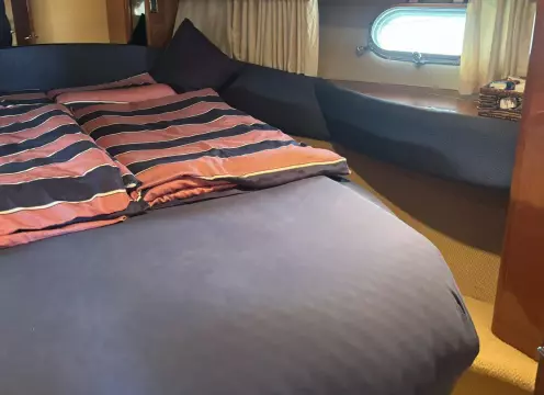 Cozy cabin interior of 2004 Princess 45 Flybridge yacht with striped bedding.