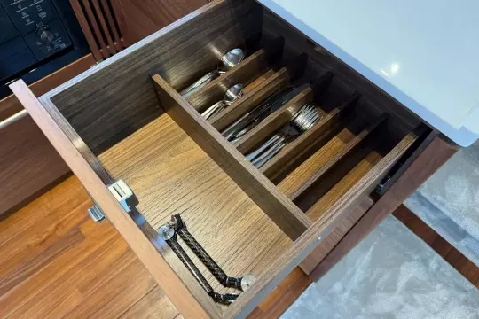 Wooden cutlery drawer in a 2024 Princess F50 yacht kitchen, featuring organized utensils.