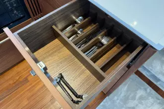 Wooden cutlery drawer in a 2024 Princess F50 yacht kitchen, featuring organized utensils.