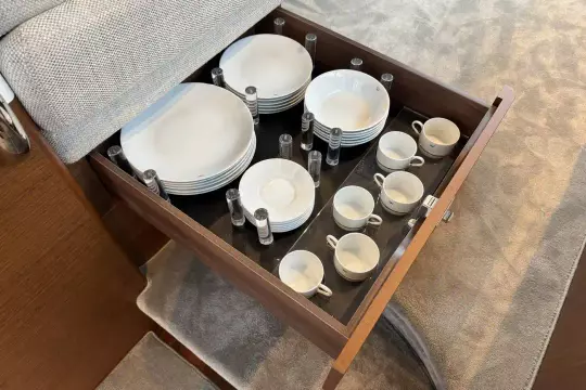 Drawer with neatly organized white dishes and cups in a 2024 Princess F50 yacht.