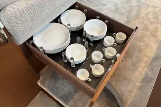 Drawer with neatly organized white dishes and cups in a 2024 Princess F50 yacht.