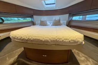 Luxurious interior of 2024 Princess F50 yacht with elegant bedding and wood accents.