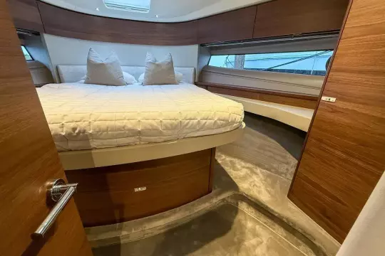 Luxurious 2024 Princess F50 yacht bedroom with elegant wood finishes and plush bedding.