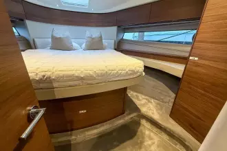 Luxurious 2024 Princess F50 yacht bedroom with elegant wood finishes and plush bedding.