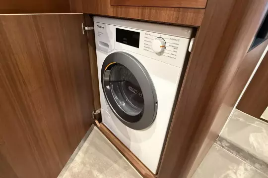 Built-in washing machine in a 2024 Princess F50 yacht's wooden cabinet.