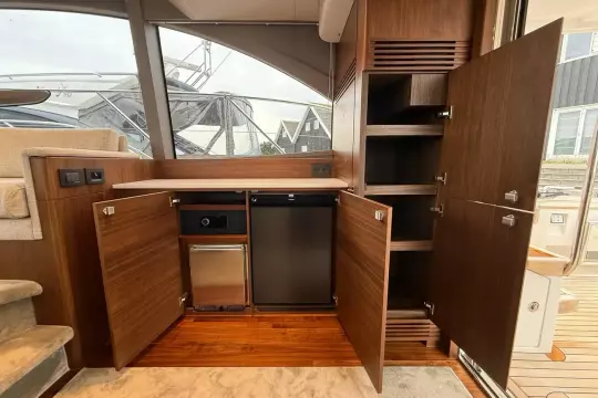 Luxurious 2024 Princess F50 yacht interior with open wooden cabinets and modern appliances.