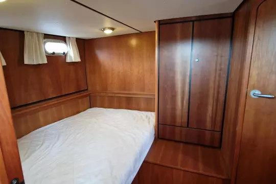 Cozy cabin interior of 2008 Linssen 33.9 AC yacht with wooden finish and bed.