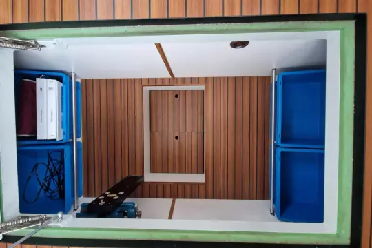 Storage compartment in a 2008 Linssen 33.9 AC boat with blue bins and wood paneling.