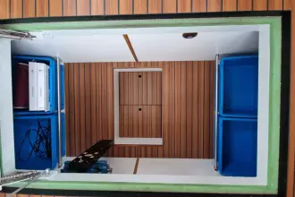 Storage compartment in a 2008 Linssen 33.9 AC boat with blue bins and wood paneling.