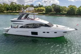 Luxurious 2015 Princess 60 yacht cruising on a serene river with lush greenery.