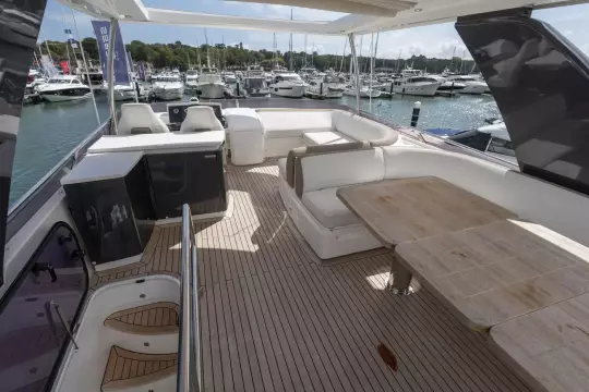 Luxurious 2015 Princess 60 yacht deck with seating and dining area, docked at marina.