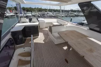 Luxurious 2015 Princess 60 yacht deck with seating and dining area, docked at marina.