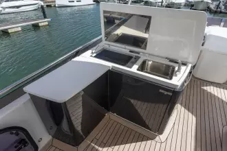 Outdoor kitchenette on 2015 Princess 60 yacht with sink and cooktop, docked at marina.