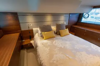 Luxurious bedroom interior of 2015 Princess 60 yacht with elegant bedding and wood accents.