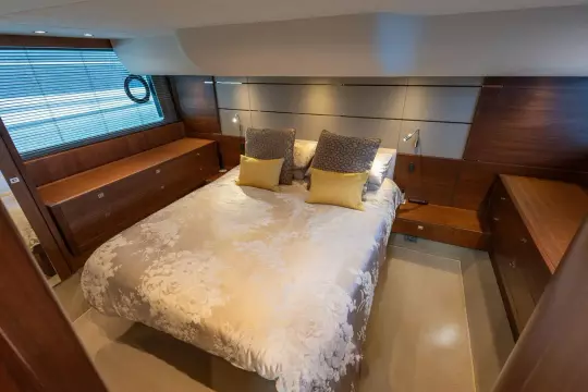 Luxurious bedroom interior on a 2015 Princess 60 yacht, featuring elegant bedding and wood accents.