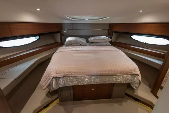 Luxurious cabin interior of 2015 Princess 60 yacht with elegant bedding and wood accents.