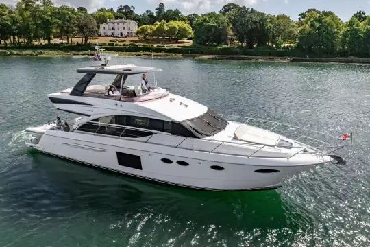 Luxurious 2015 Princess 60 yacht cruising on a serene river with lush greenery.