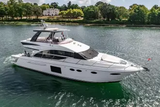 Luxurious 2015 Princess 60 yacht cruising on a serene river with lush greenery.
