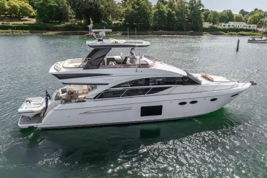 Luxury 2015 Princess 60 yacht cruising on a serene waterway, surrounded by lush greenery.