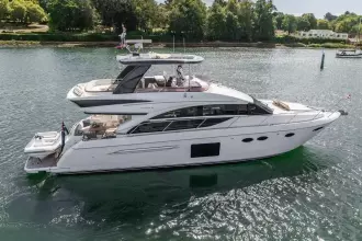 Luxury 2015 Princess 60 yacht cruising on a serene waterway, surrounded by lush greenery.