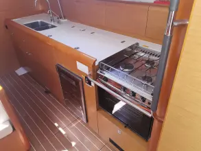 2013 Jeanneau Sun Odyssey 469 galley with stove, sink, and wooden cabinetry.