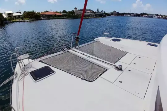 2020 Lagoon 42 catamaran on calm water, featuring spacious deck and netting.