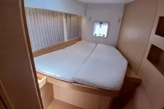 2020 Lagoon 42 yacht cabin with cozy bed, window, and wooden interior.