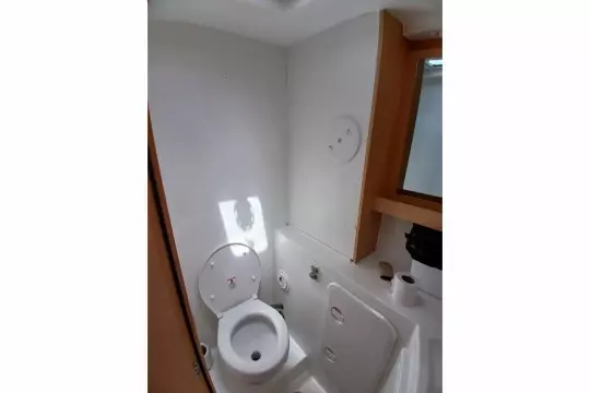 2020 Lagoon 42 yacht bathroom with toilet, mirror, and storage.