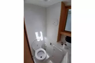 2020 Lagoon 42 yacht bathroom with toilet, mirror, and storage.