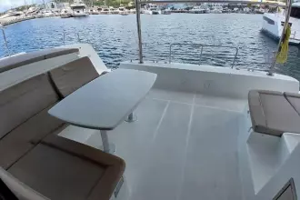 Spacious deck of 2020 Lagoon 42 catamaran with seating and table, docked at marina.