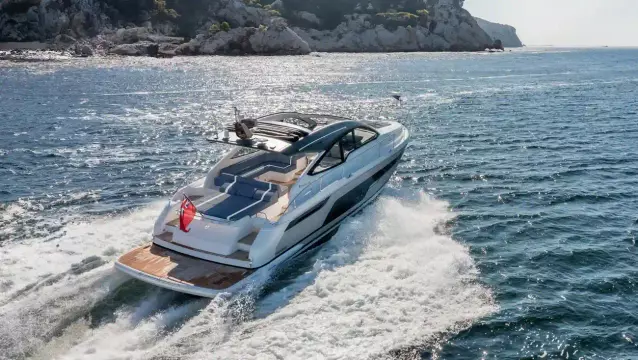 2025 Fairline Targa 50 Open yacht cruising on the ocean near rocky coastline.