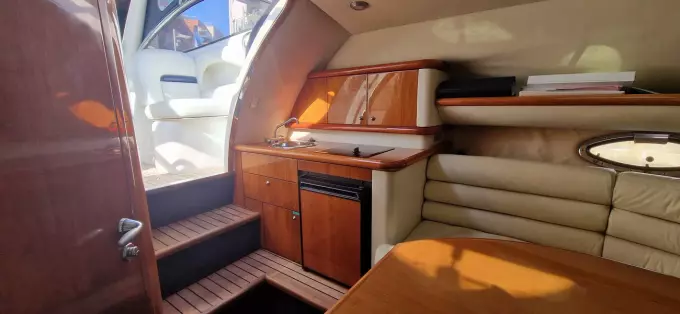 Interior of 2003 Sunseeker Superhawk 34 yacht, featuring wood cabinetry and seating area.