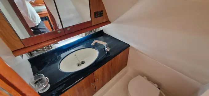 2003 Sunseeker Superhawk 34 bathroom with sleek sink, mirror, and wooden cabinetry.