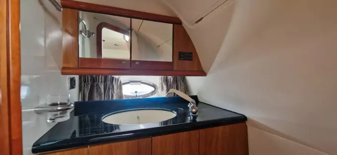 2003 Sunseeker Superhawk 34 yacht bathroom with wooden cabinets and sleek black countertop.