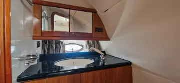 2003 Sunseeker Superhawk 34 yacht bathroom with wooden cabinets and sleek black countertop.
