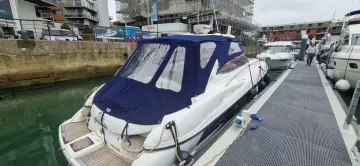 2003 Sunseeker Superhawk 34 yacht docked at marina with blue canopy.