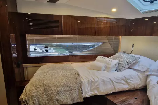 Luxurious cabin interior of 2024 Fairline Targa 45 Open yacht, featuring elegant bedding and wood finishes.