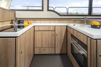 Modern kitchen interior of 2025 Linssen 45 SL Sedan yacht, featuring sleek wood cabinetry.